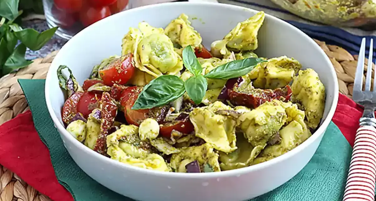Miseczka tortellini z pesto, pomidorkami koktajlowymi i bazylią.