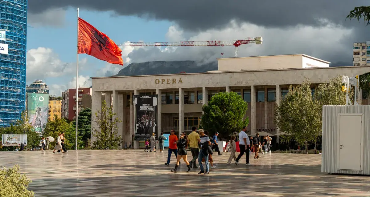 Plac przed Operą w Tiranie, z albańską flagą. Warto zobaczyć to miejsce, spacerując po centrum.