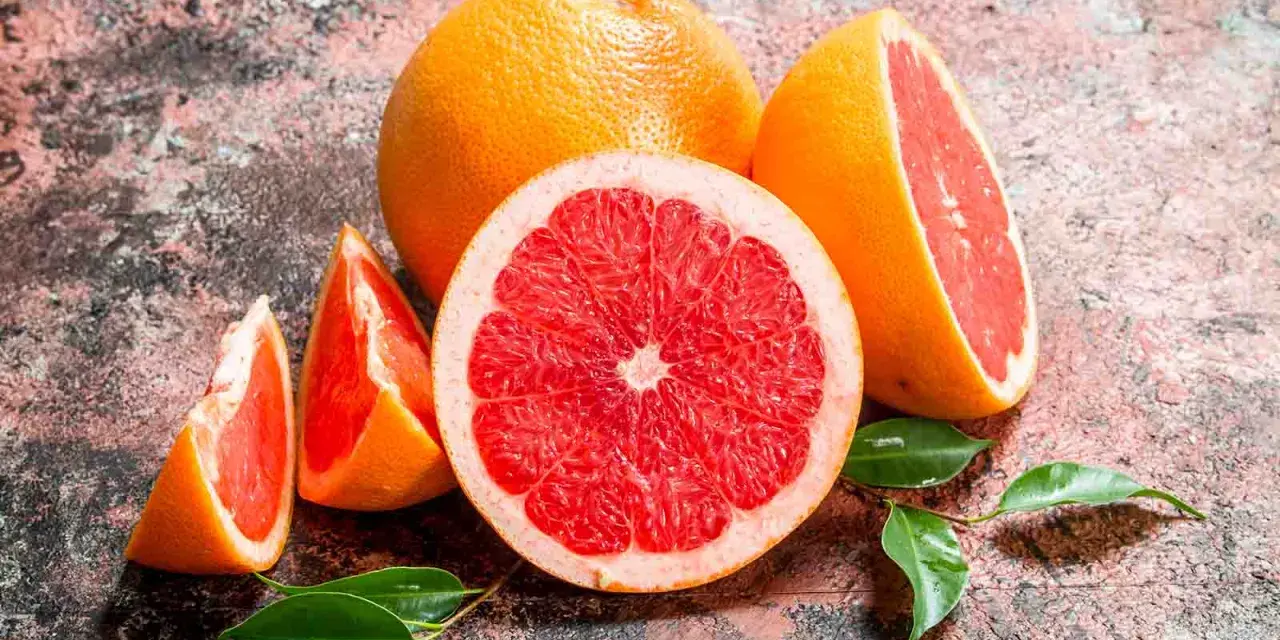 Saftige Grapefruits, frisch aufgeschnitten und als Spalten, mit grünen Blättern. Grapefruit gesund und lecker.