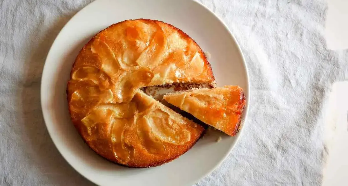 Tarta de manzana esponjosa, dorada y jugosa, con una porción recién cortada lista para disfrutar.