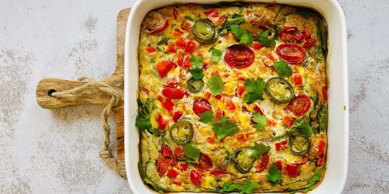 Pyszny omlet z piekarnika z pomidorkami, papryką i jalapeño, udekorowany natką pietruszki.
