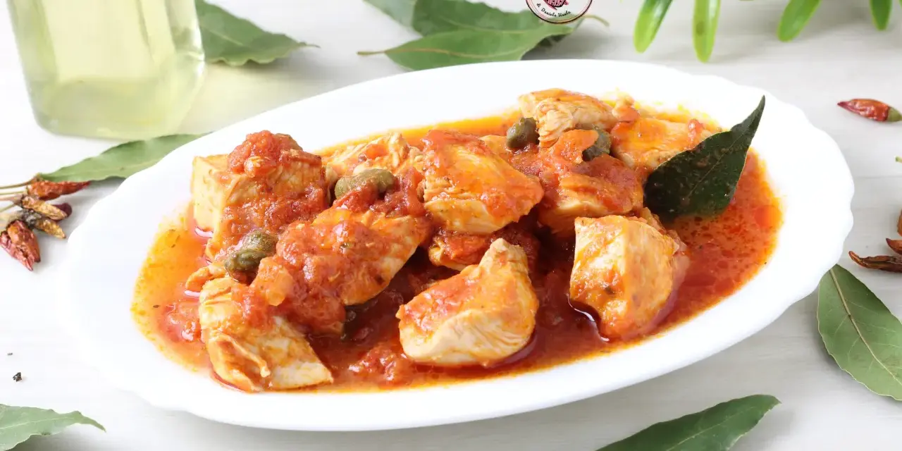 Un invitante pollo alla pizzaiola, con pezzi succulenti immersi in una ricca salsa di pomodoro, capperi e profumate foglie di alloro.