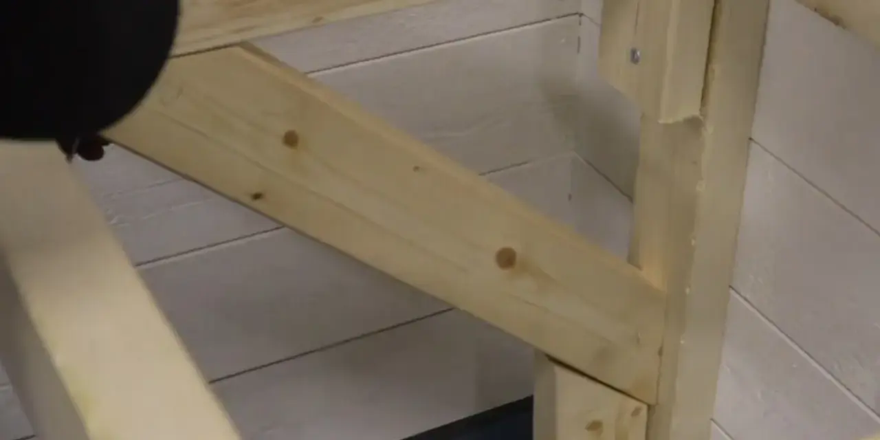 En person håller på att såga snett en träbit som ska bli en del av en konstruktion.