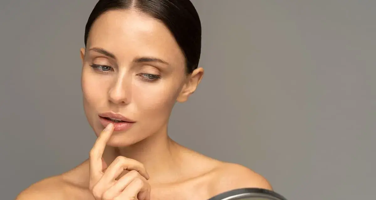 Mujer se toca los labios con el dedo, reflexionando sobre cómo hidratar los labios para una piel radiante.