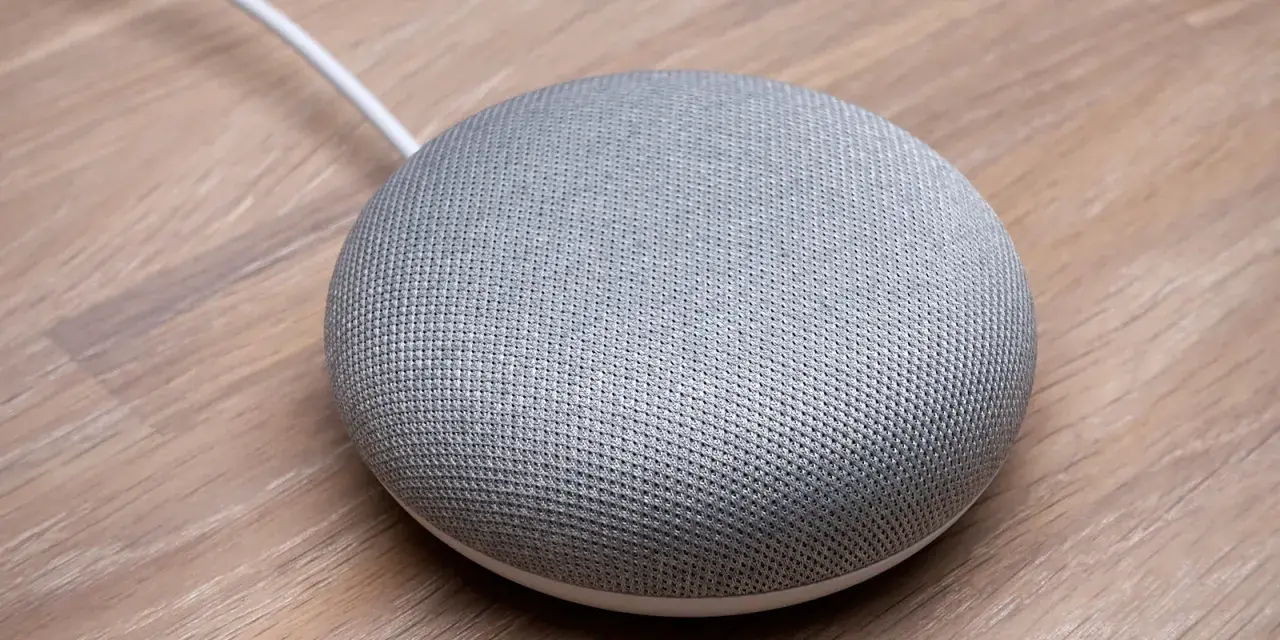 En grå Google Home Mini på ett trägolv, redo att styra ditt smarta hem med Verisure.
