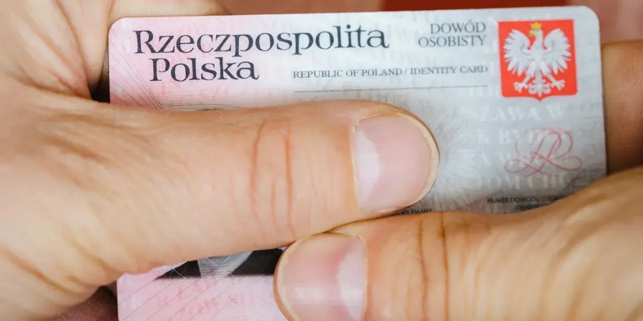Dłonie trzymają polski dowód osobisty. Widoczny jest numer dowodu osobistego.