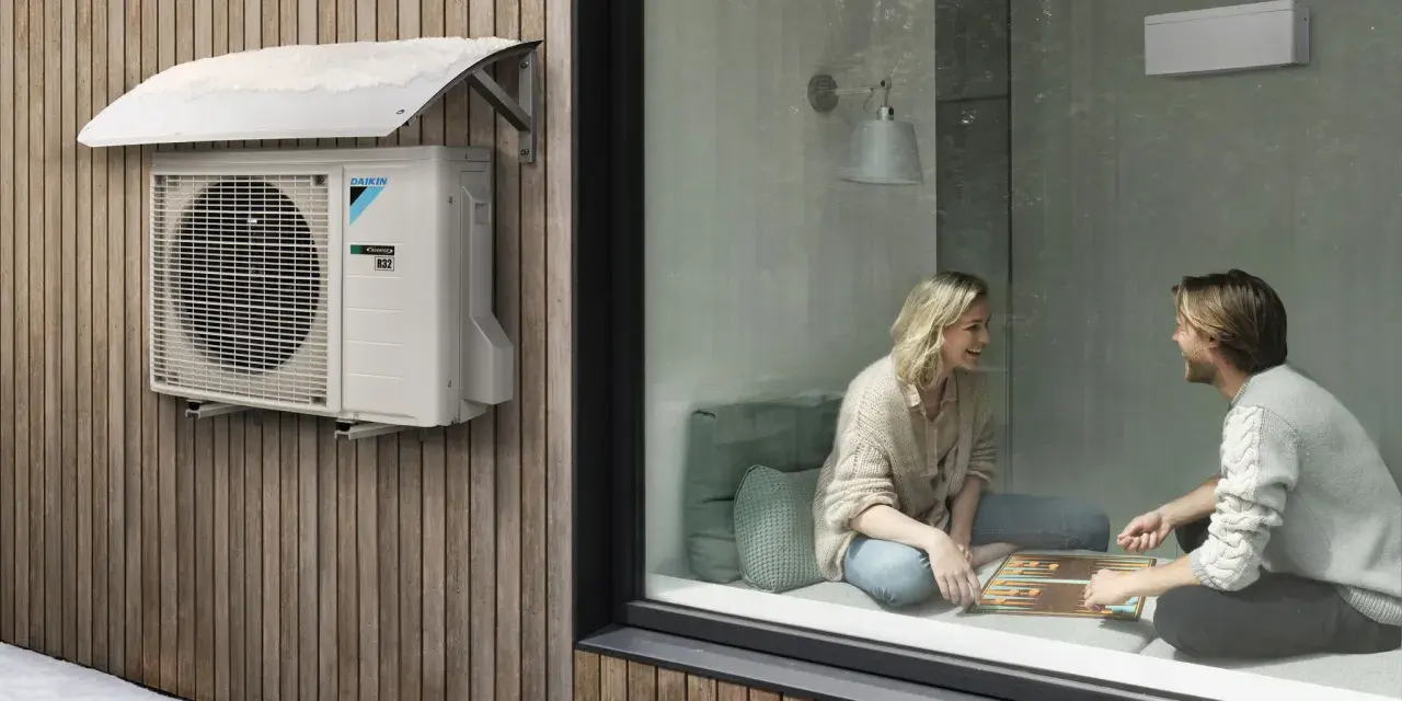 Unidad exterior de aire acondicionado Daikin instalada bajo un alero protector en una pared de madera. Ideal para saber donde colocar la unidad exterior del aire acondicionado.