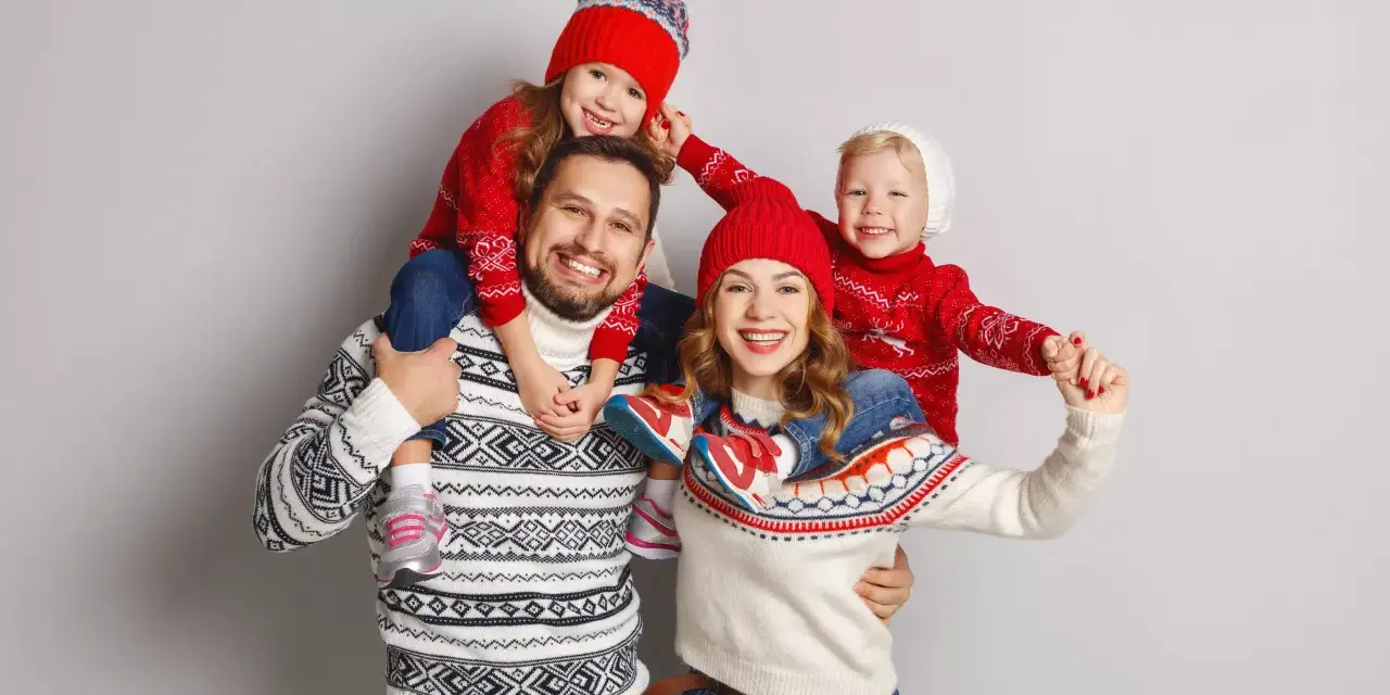 Famiglia felice con maglioni natalizi coordinati, un'ottima ispirazione per idee outfit natale.