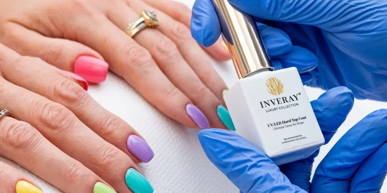 Kolorowy manicure hybrydowy krok po kroku. Dłoń z paznokciami w pastelowych barwach, kosmetyczka trzyma buteleczkę lakieru.