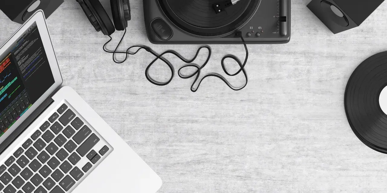 Laptop z programem do produkcji muzyki, gramofon, słuchawki i głośniki. Tworzenie utworu muzycznego z samplera.