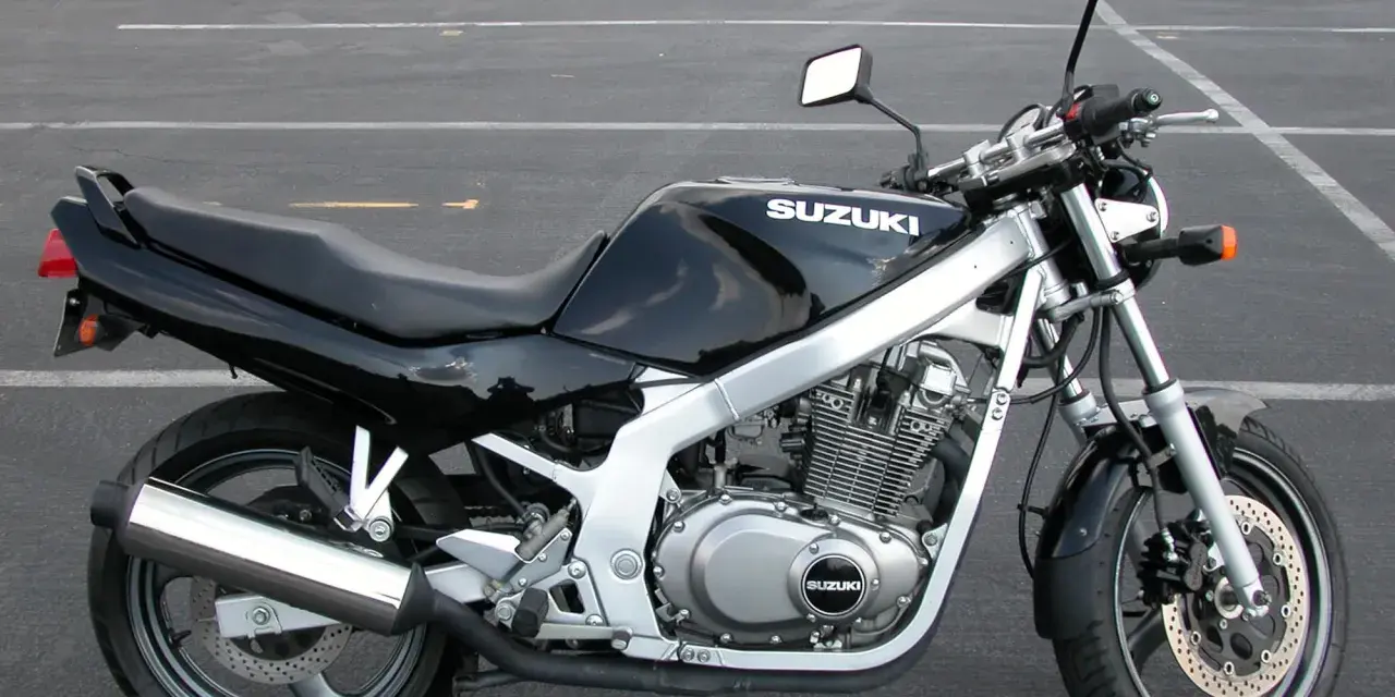 Czarny motocykl Suzuki GS 500 z chromowanym wydechem stoi na pustym parkingu.
