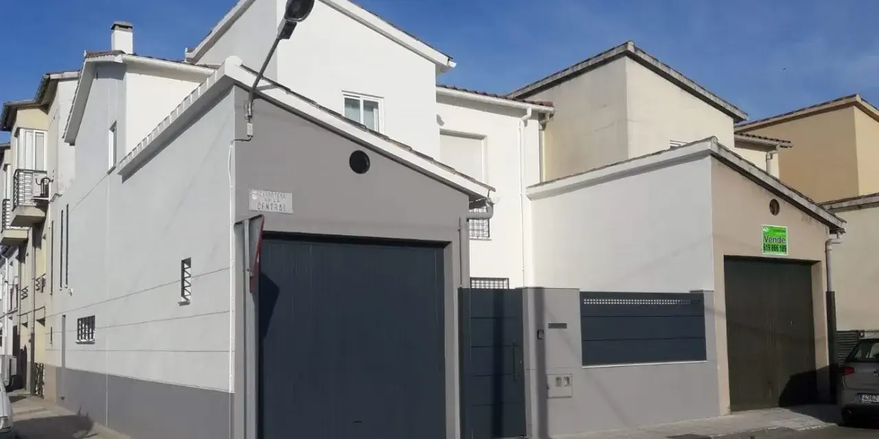 Fachada de casa con garaje, lista para como pintar una pared exterior en mal estado.