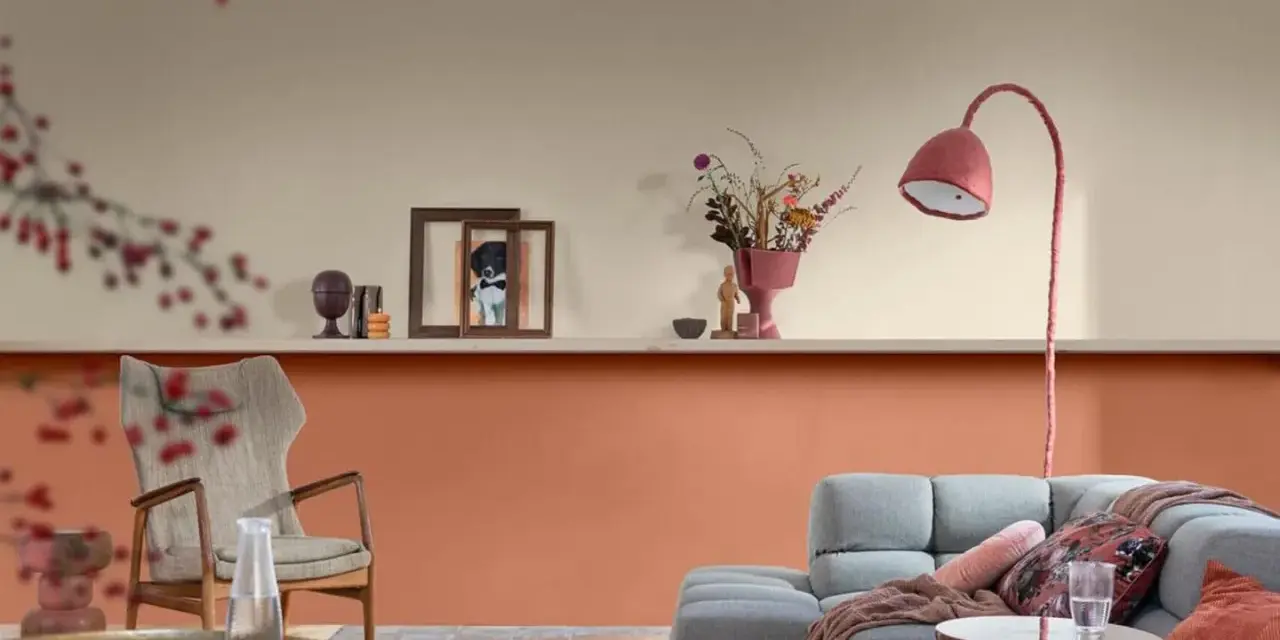 Soggiorno con pareti bicolore: la parte inferiore è color terracotta, quella superiore color crema. Arredamento moderno con divano grigio e poltrona.
