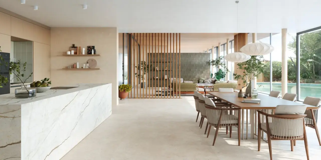 Ampio open space con cucina moderna, isola in marmo e zona pranzo. Pavimenti diversi creano continuità visiva tra gli ambienti.
