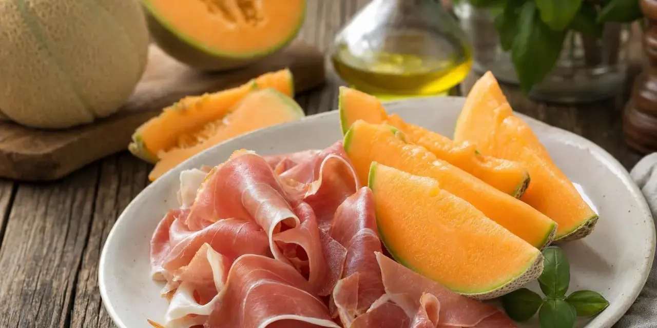 Piatto con fette di prosciutto e spicchi di melone, un classico antipasto italiano.