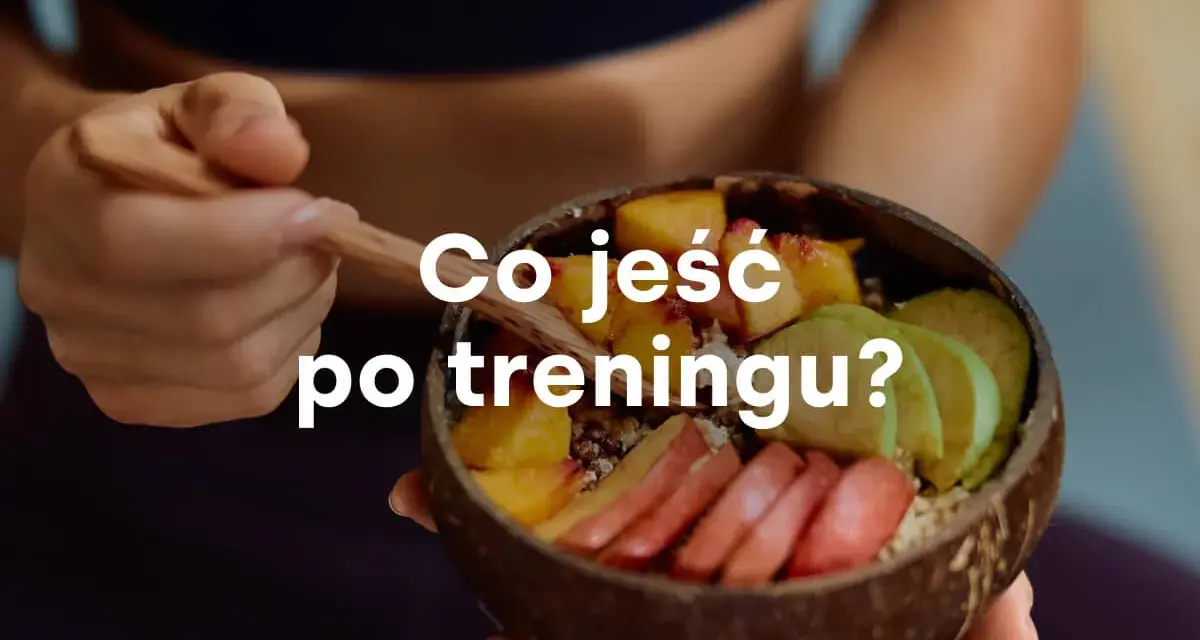 Miseczka z owocami i napisem "Co jeść po treningu?". Zdrowy posiłek regeneracyjny.