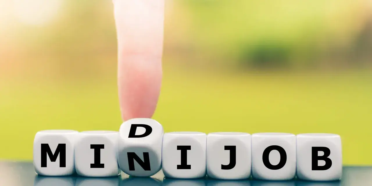 Würfel zeigen "MINIJOB". Ein Finger dreht den Würfel mit "D" zu "N", um "MINIJOB" zu bilden. Ideal für flexible Stunden pro Woche.
