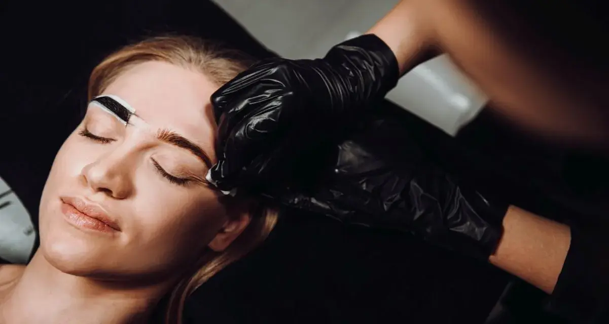 Stylistka w czarnej rękawiczce precyzyjnie maluje brwi klientce. Zastanawiasz się, co ile henna brwi daje najlepsze efekty?