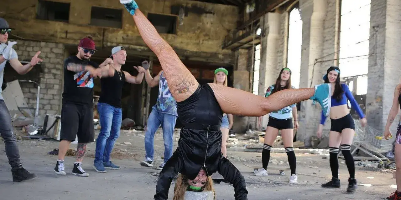 Grupa młodych ludzi tańczy w opuszczonym budynku. Jedna z dziewczyn wykonuje efektowną figurę, stojąc na rękach. To właśnie dancehall!