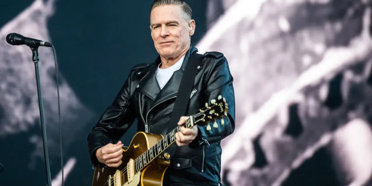 Bryan Adams w skórzanej kurtce gra na gitarze, przypominając piosenkę z Robin Hooda.