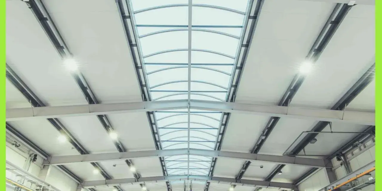 Interno di un capannone con luminose coperture industriali e lucernari curvi che illuminano lo spazio.