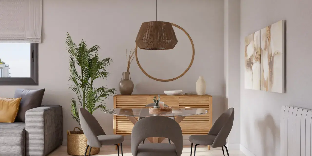 Acogedor salon comedor muy pequeño con sofá gris, mesa redonda de cristal y sillas tapizadas. Decoración natural con planta y cesta.