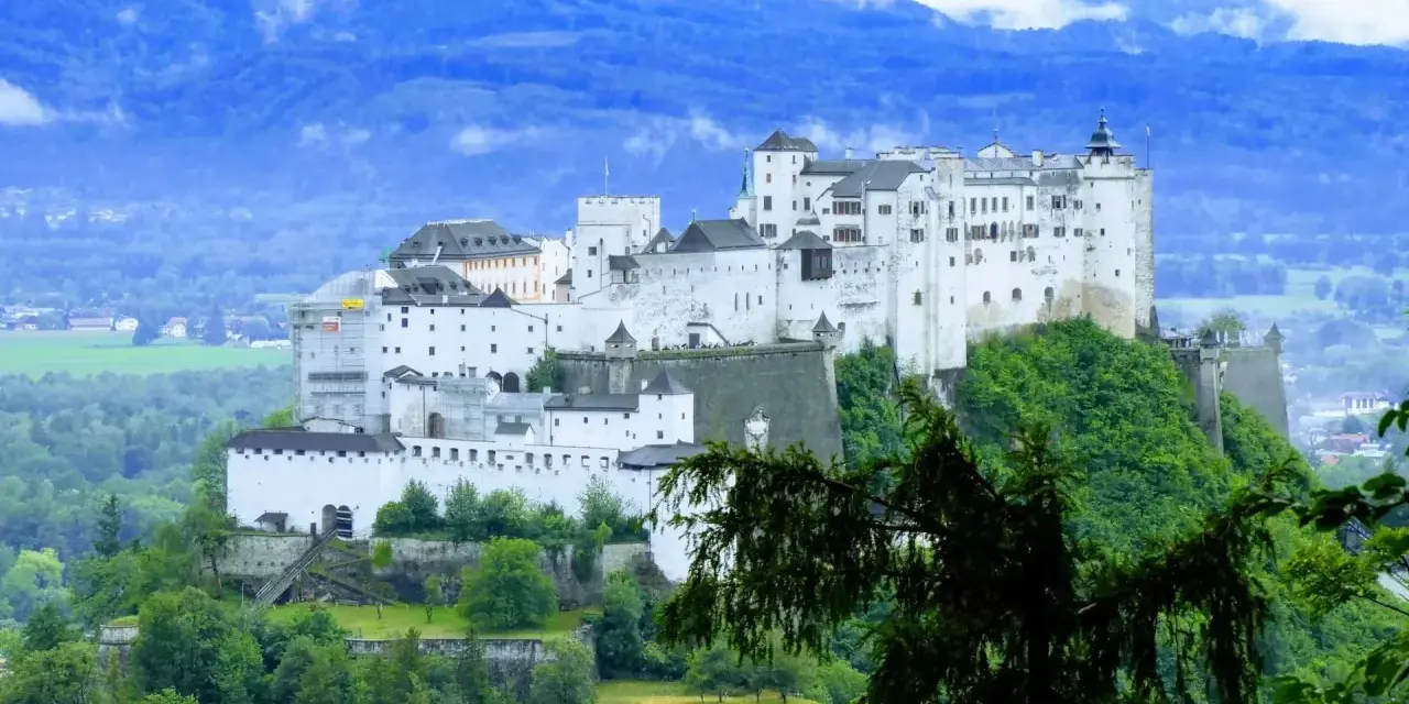 Majestatyczna twierdza Hohensalzburg, obowiązkowy punkt na liście "Salzburg co zobaczyć", góruje nad zielonymi wzgórzami i miastem.