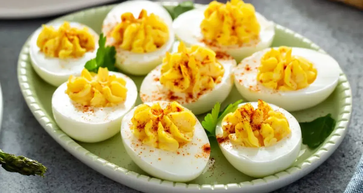 Oeufs mimosa au thon, garniture jaune crémeuse saupoudrée de paprika sur des blancs d'œufs sur une assiette verte.