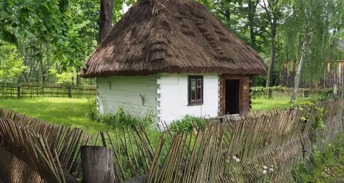 Drewniana chata z krytym strzechą dachem i płotem z gałęzi. Wspaniałe radom atrakcje, które przenoszą w przeszłość.