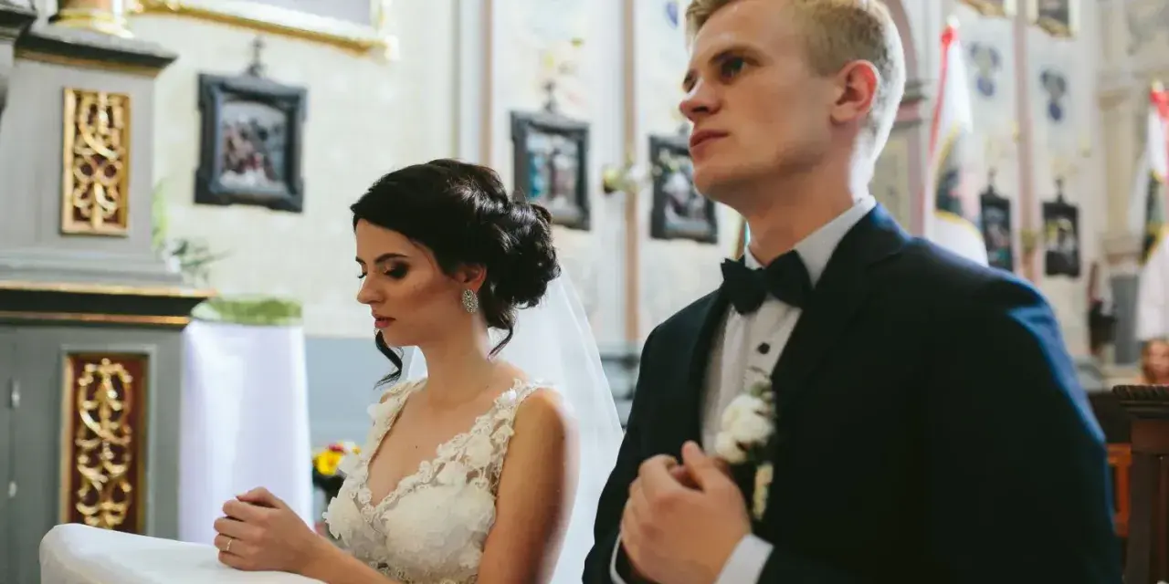 Para młoda w kościele. Czy można zmienić parafię? Panna młoda w białej sukni, pan młody w garniturze.