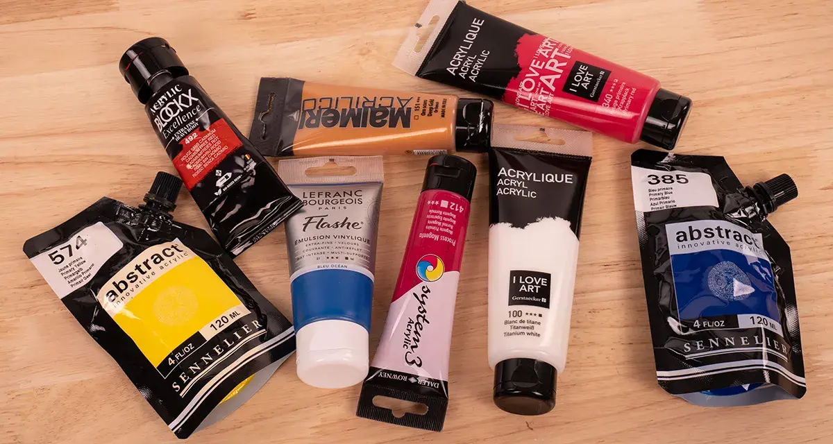 Des tubes de peinture acrylique de diverses couleurs et marques, prêts à se mettre à la peinture.