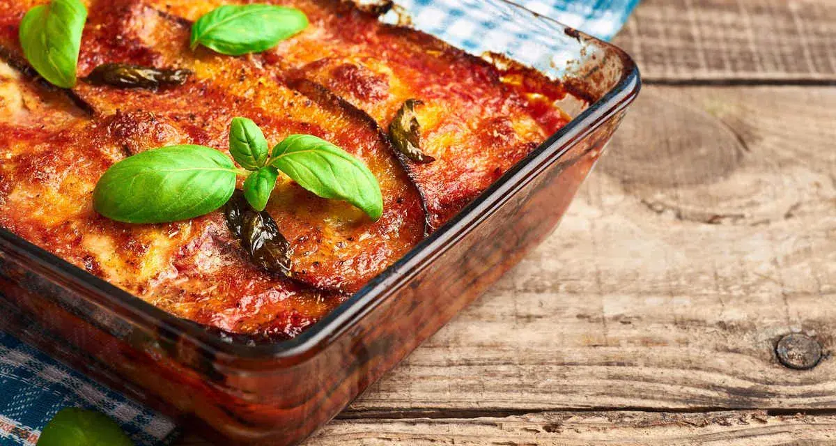 Parmigiana di melanzane in friggitrice ad aria, dorata e profumata, guarnita con basilico fresco. Un piatto gustoso e leggero.