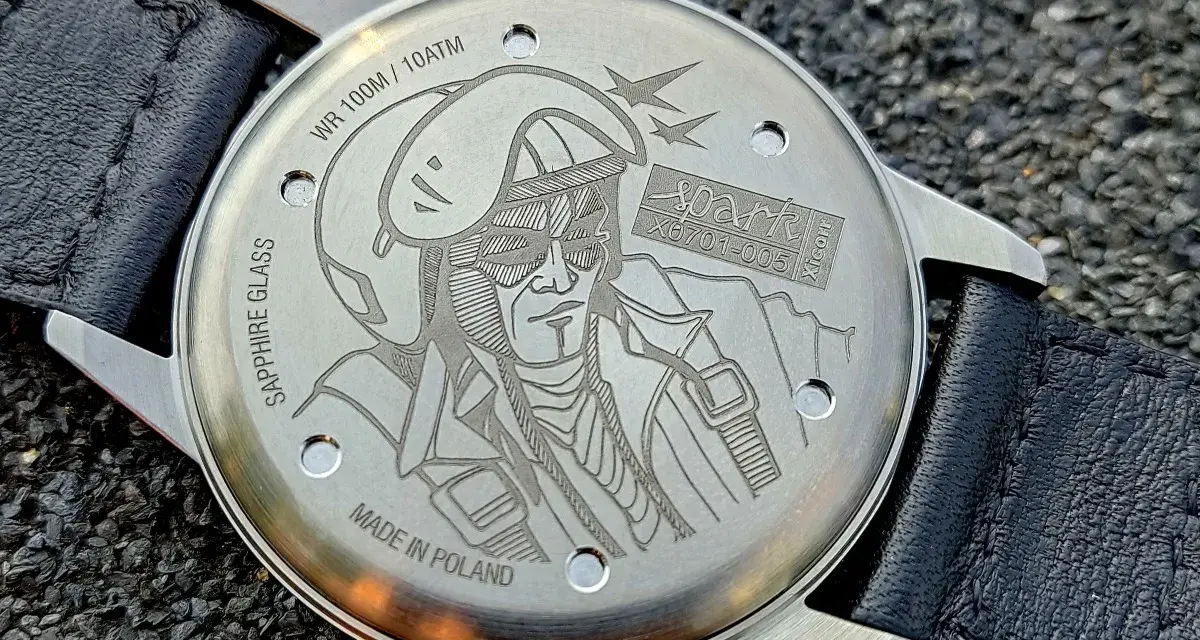 Napis na deklu zegarka: "MADE IN POLAND", WR 100M/10ATM, SAPPHIRE GLASS. Grawer przedstawia pilota w hełmie i goglach.