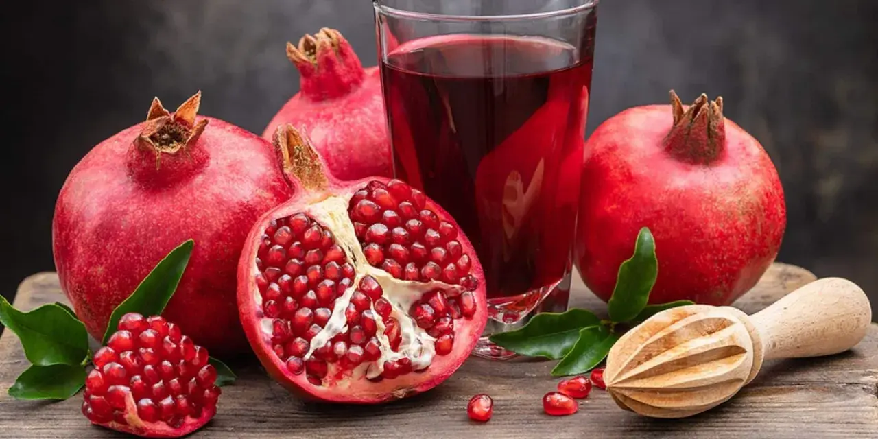 Frische Granatäpfel und Saft auf einem Holztisch. Ein gesunder Genuss, besonders in der Schwangerschaft.