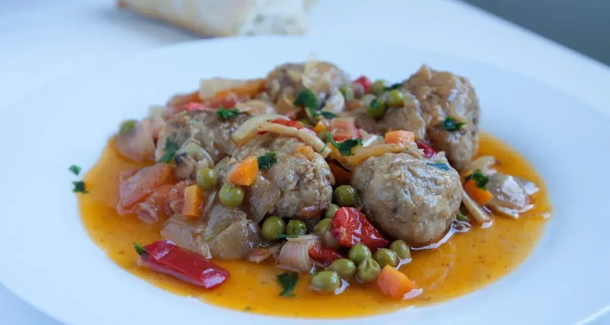 Albondigas a la jardinera, jugosas y sabrosas, con guisantes, zanahoria y pimiento rojo en una salsa dorada.