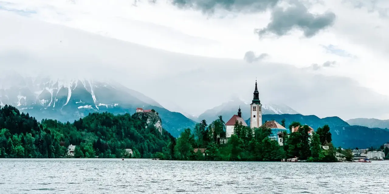 Jezioro Bled ze słynną wyspą i kościołem to obowiązkowy punkt, co warto zobaczyć w Słowenii. W tle góry.