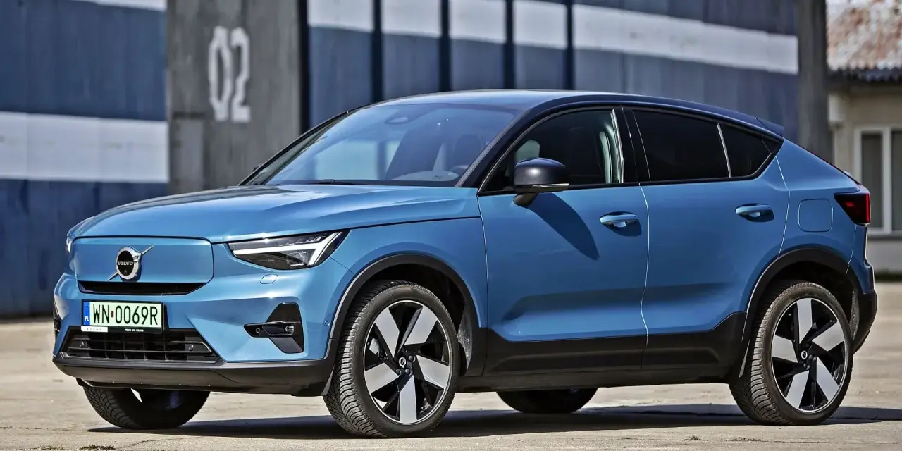 Niebieskie Volvo C40, elektryczny SUV coupe, parkuje przed budynkiem z numerem "02".