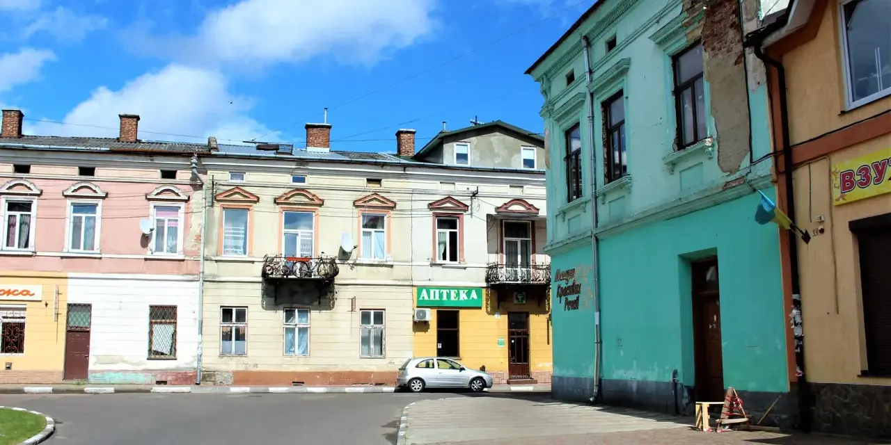 Kolorowe kamienice przy ulicy, gdzie mój stryj kiedyś mieszkał. Srebrny samochód zaparkowany obok apteki.