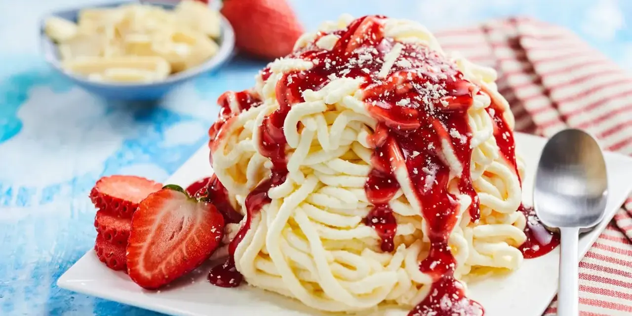Ein köstliches Spaghetti-Eis-Dessert mit Erdbeersoße und frischen Erdbeeren, bereit zum Genießen.
