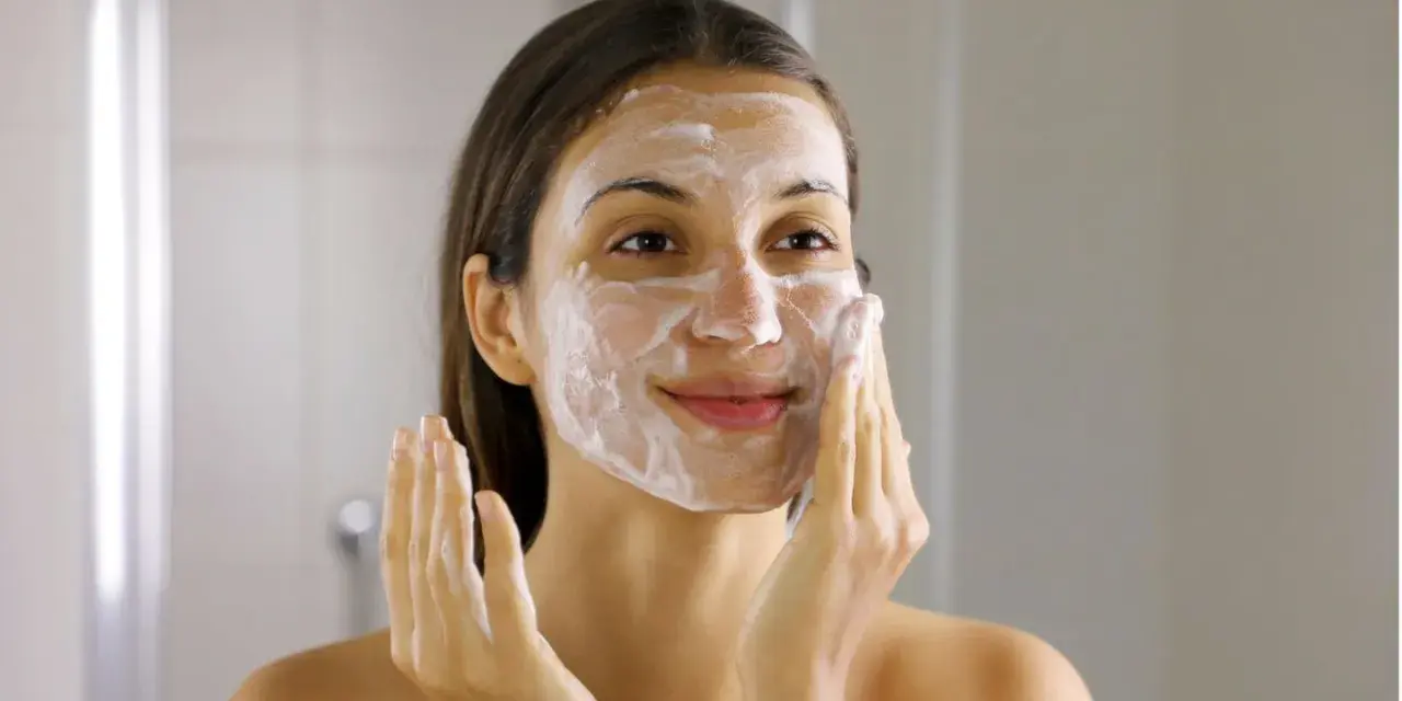 Frau mit Schaum im Gesicht, die ihre Haut reinigt. Ein Schritt im Double Cleansing für reine Haut.