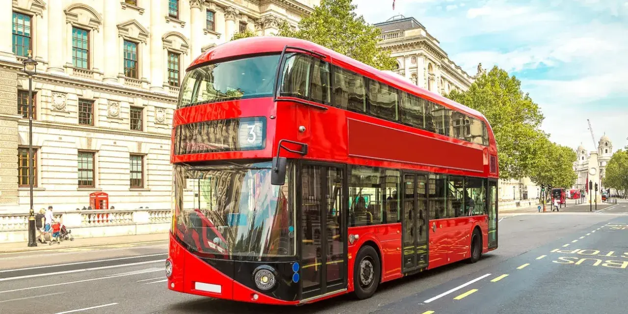 Ikoniczny czerwony autobus piętrowy na ulicy w Londynie, symbol komunikacji miejskiej.