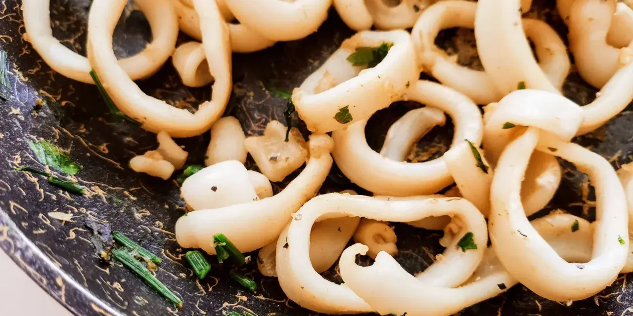 Anelli di totano in padella, dorati e profumati con erbe aromatiche, pronti per essere gustati.