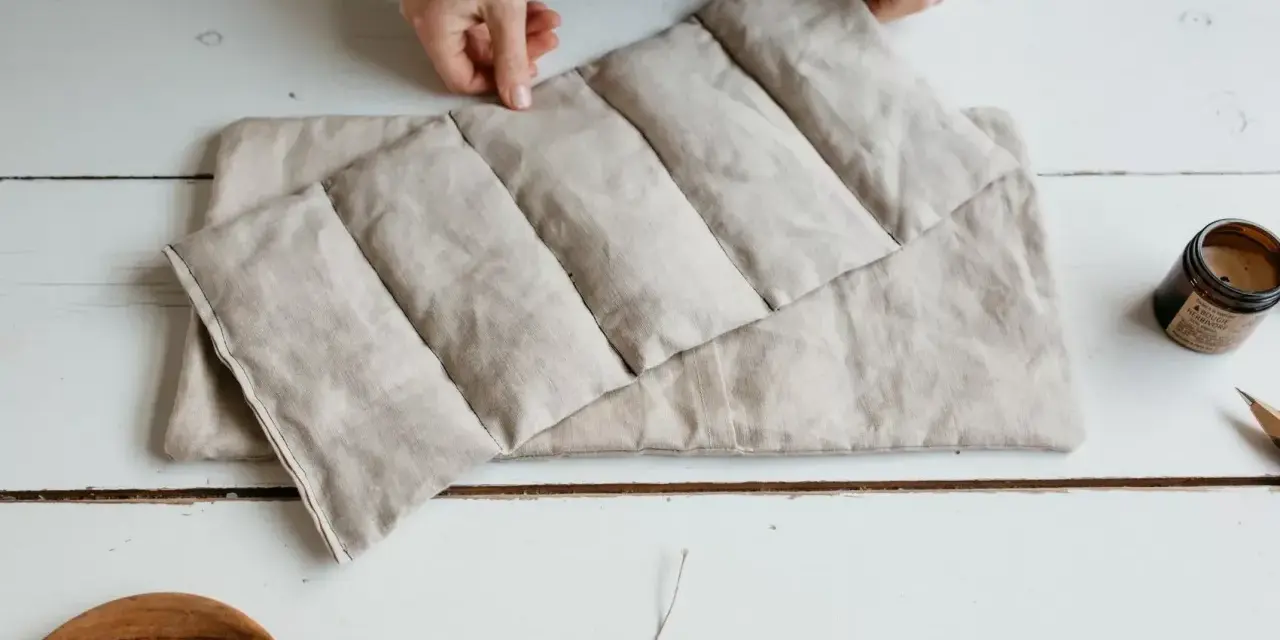 Mains tenant une bouillotte graines de lin, prête à soulager les tensions. Un objet doux et naturel pour le bien-être.