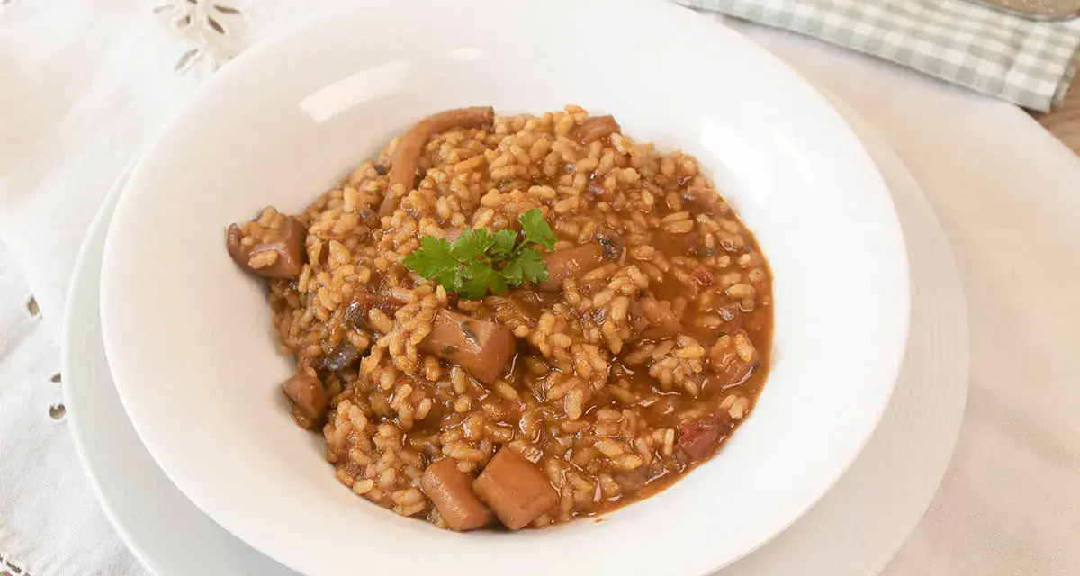 Arroz con sepia en un plato blanco, decorado con perejil.