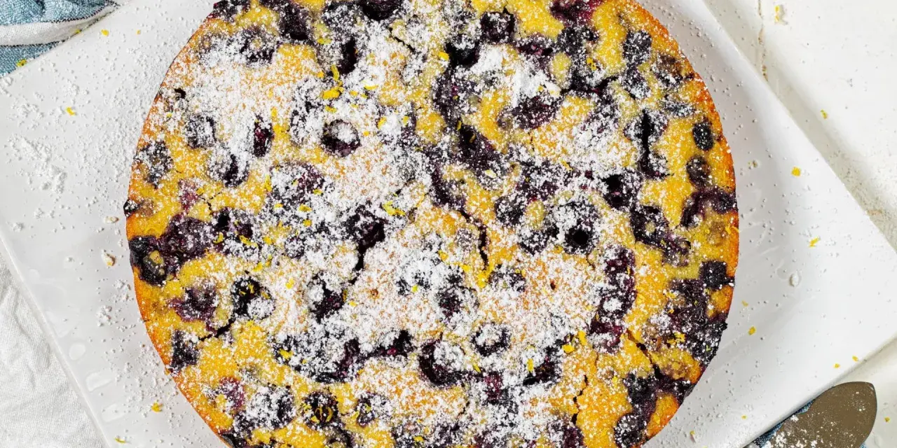 Ein köstlicher glutenfreier Kuchen mit Blaubeeren und Puderzucker bestreut, bereit zum Genießen.