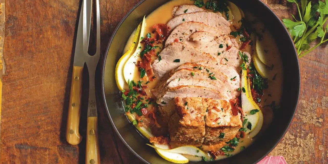 Lonza di maiale in padella morbida, affettata e servita con pere, salsa cremosa e prezzemolo tritato.