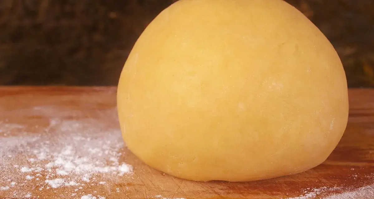 Impasto giallo dorato, pronto per diventare la base perfetta per una deliziosa pasta frolla per pastiera.