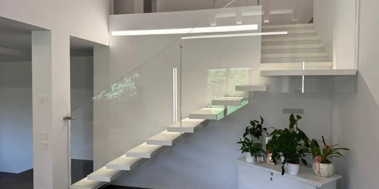 Moderna scala interna con gradini sospesi e parapetto in vetro, un esempio di come la normativa scale interne uso privato possa ispirare design eleganti e sicuri.