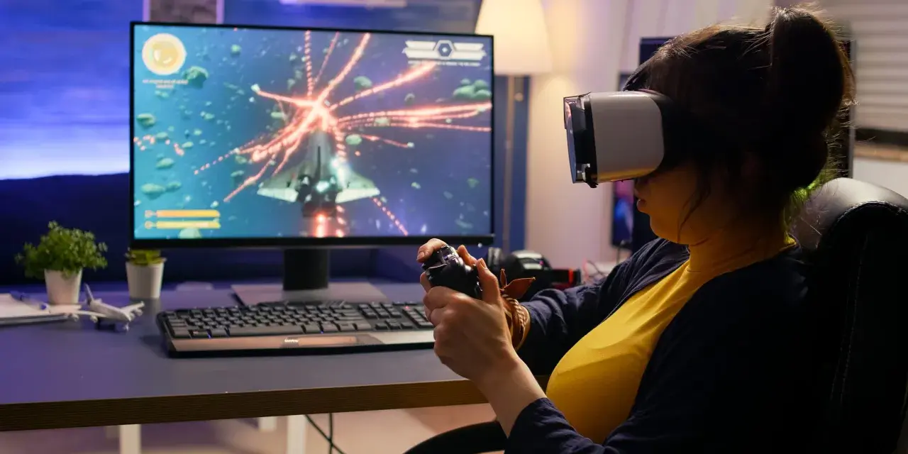 Kobieta w goglach VR gra w kosmiczną strzelankę, testując swoje umiejętności w ramach studiów game design.