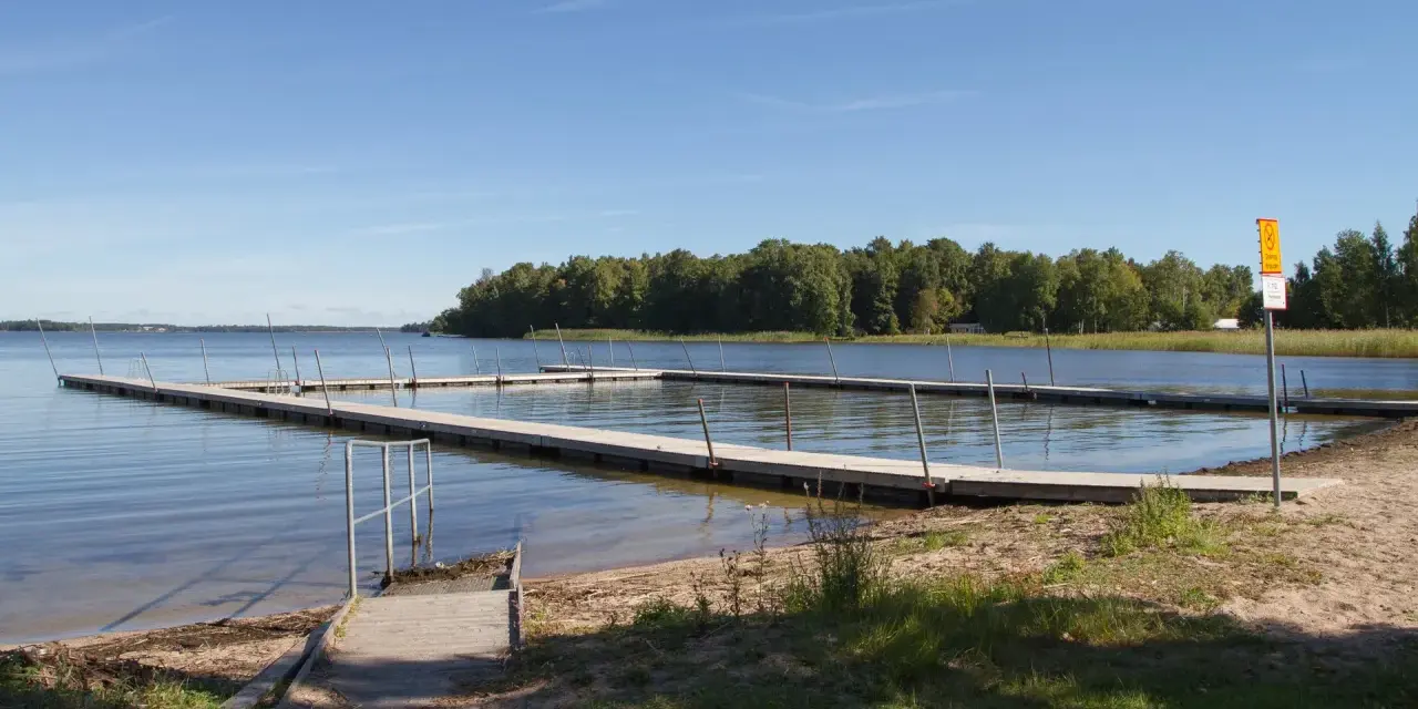 Bryggor vid Hampetorp camping. Solig dag med klarblå himmel över sjön.